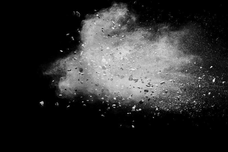 Split debris of stone exploding with white powder against black background