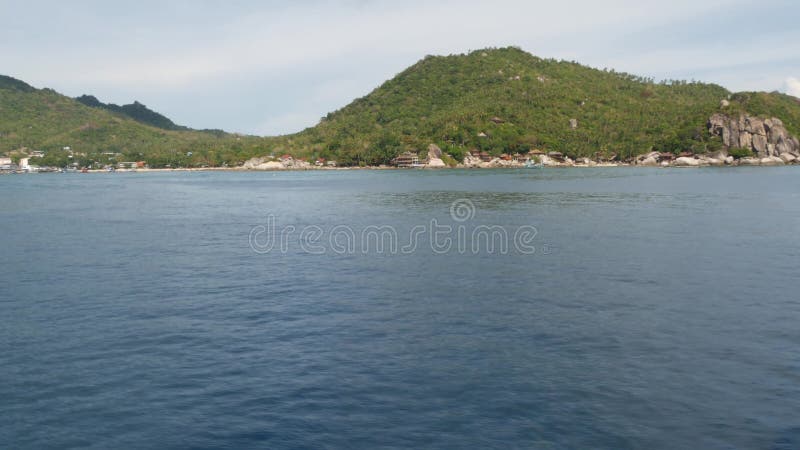Spokojna woda w pobliżu zielonej, tropikalnej wyspy raju Spokojna woda morska w pobliżu kurortu nurkowego na pagórkowatej wyspie