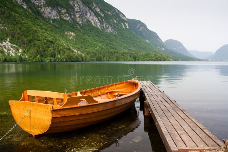 boat berth by the tranquil lake pier with mountain as background. boat berth by the tranquil lake pier with mountain as background