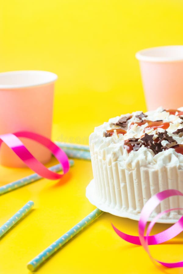 Sponge layer birthday cake with whipped cream frosting chocolate star sprinkles strawberry confiture. Pink paper drinking cups royalty free stock photos Sponge layer birthday cake with whipped cream frosting chocolate star sprinkles strawberry confiture. Pink paper drinking cups royalty free stock photos