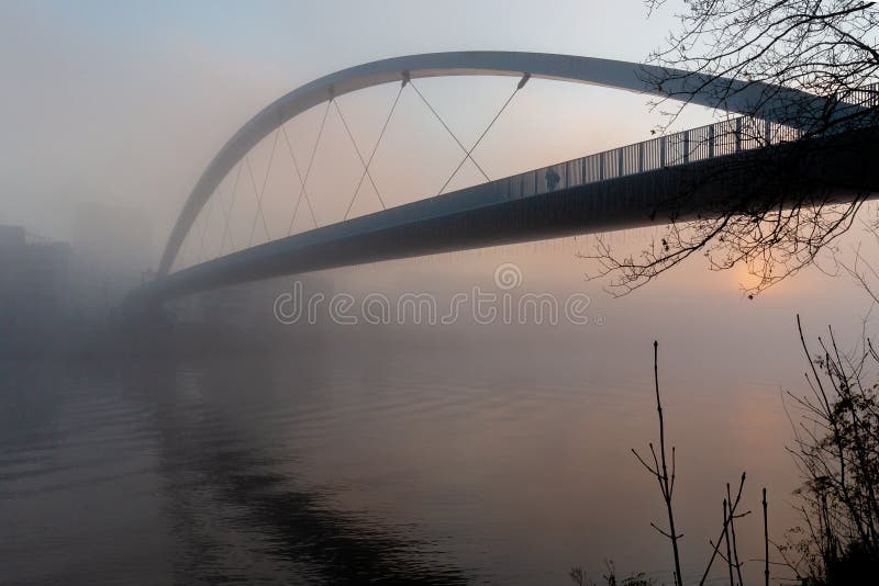 Las luces alto puente inglés traducción recubrimiento la ciudad centro de sobre el frío manana niebla través de un rio.