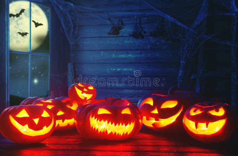 Spooky halloween background. scary pumpkin with burning eyes and smiles in the night