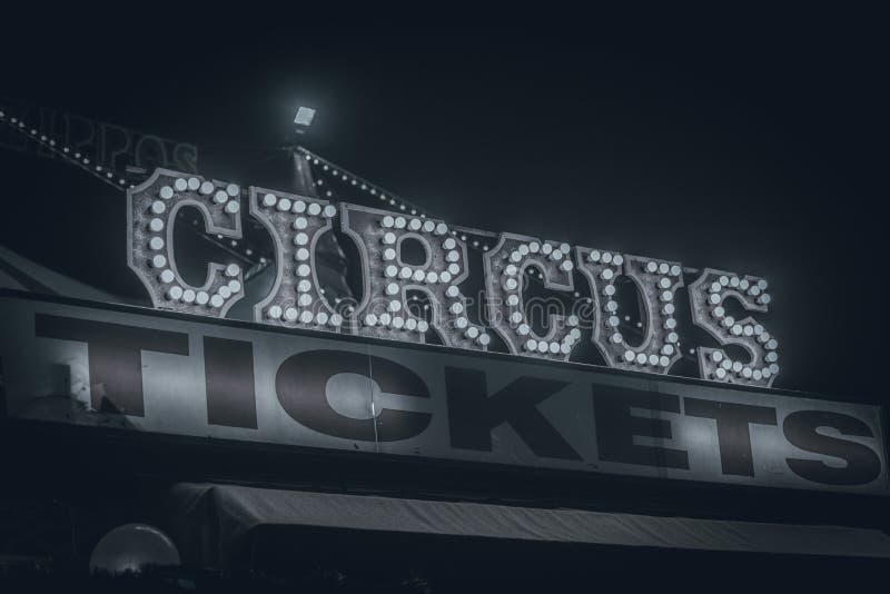 Spooky old dimly lit circus sign with light bulbs in dark fog over a ticket stand. Typical view of an entrance to a circus.