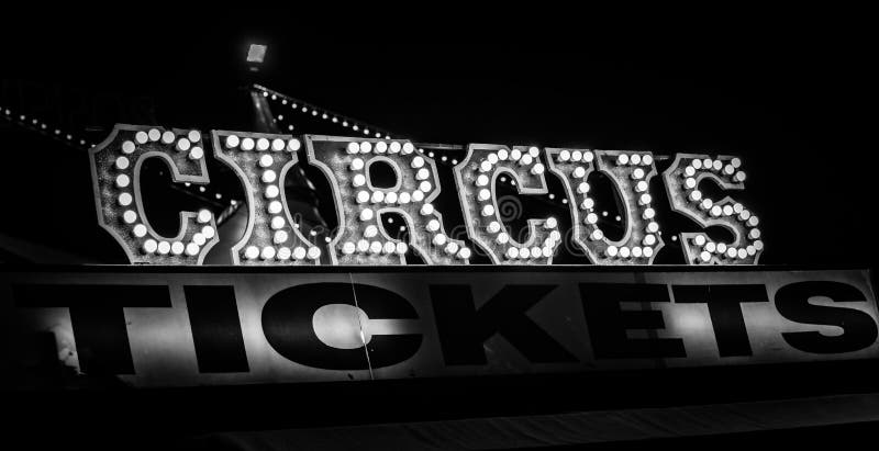 Spooky old dimly lit circus sign with light bulbs in the dark over a ticket stand in black and white. Typical view of an entrance