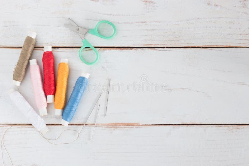Spool of thread many color with needle and small Scissors. Top view, Spool of thread many color with needle and small Scissors on white wood board, copy space royalty free stock photo Spool of thread many color with needle and small Scissors. Top view, Spool of thread many color with needle and small Scissors on white wood board, copy space royalty free stock photo