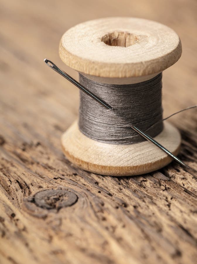 Black Thread on an Old Wooden Spool and Sewing Needle Stock