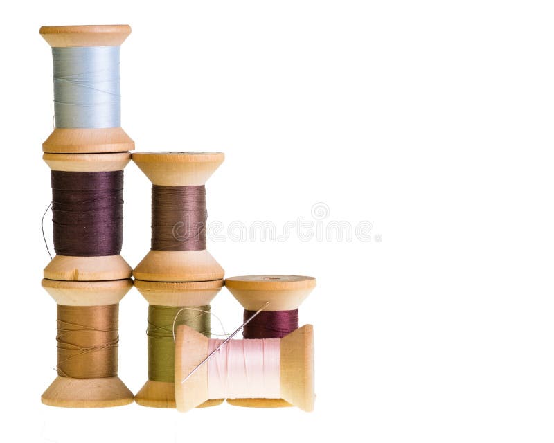 Wooden spools of sewing thread with a needle isolated on white. Wooden spools of sewing thread with a needle isolated on white