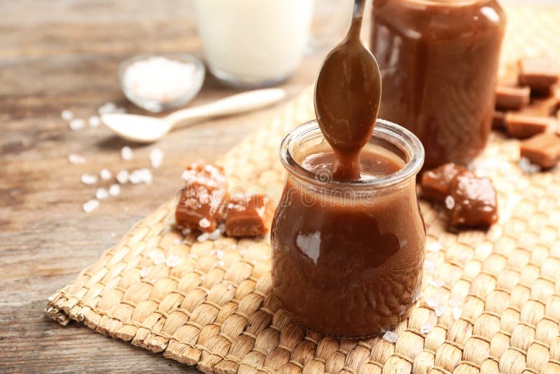 Spoon of Caramel Sauce Above Jar on Wooden Table Stock Image Image of