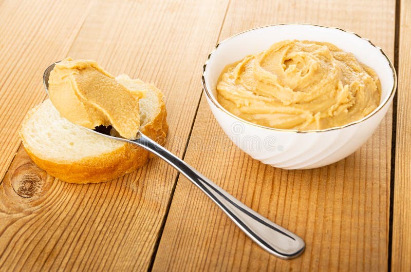 Spoon with Paste on Bread, Peanut Butter in Bowl on Wooden Table Stock