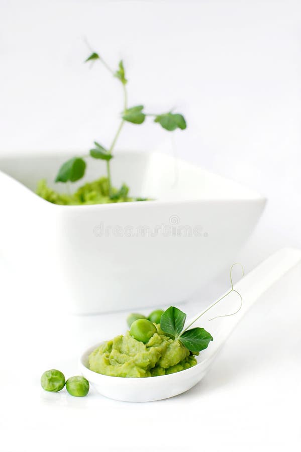 A green pea puree with a pea sprout in a white spoon. A green pea puree with a pea sprout in a white spoon.