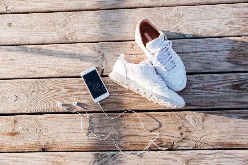 Sport concept - pair of white sneakers, smartphone and earphones royalty free stock images Sport concept - pair of white sneakers, smartphone and earphones royalty free stock images