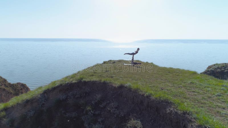 Sport de yoga, famille d'athlètes de yogi exécuter l'extérieur de équilibrage appareillé d'exercices sur la falaise près de la me