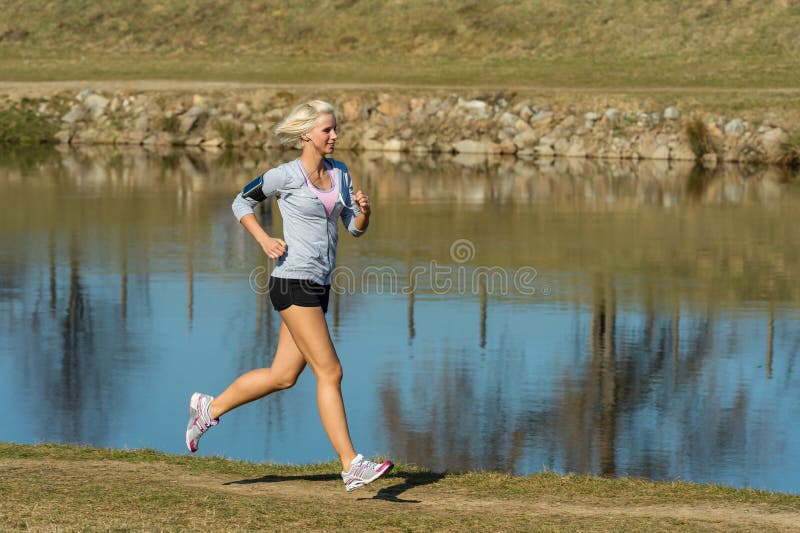 Sport esterno della donna corrente dalla banca di fiume immagini stock Sport esterno della donna corrente dalla banca di fiume immagini stock