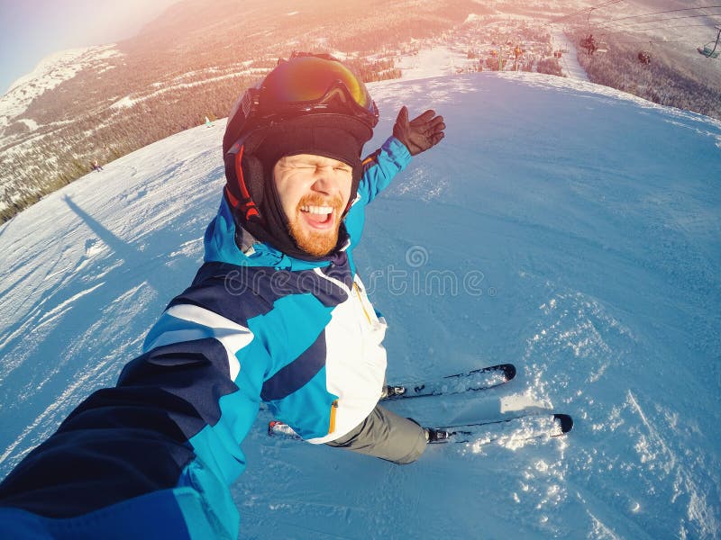 Sport estremo di inverno con la macchina fotografica di azione del selfie Giri dell'uomo sugli sci dei pendii in casco protettivo immagini stock Sport estremo di inverno con la macchina fotografica di azione del selfie Giri dell'uomo sugli sci dei pendii in casco protettivo immagini stock