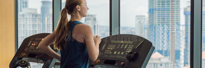 Sport, fitness, lifestyle, technology and people concept - woman exercising on treadmill in gym against the background of a big city. BANNER, long format. Sport, fitness, lifestyle, technology and people concept - woman exercising on treadmill in gym against the background of a big city. BANNER, long format