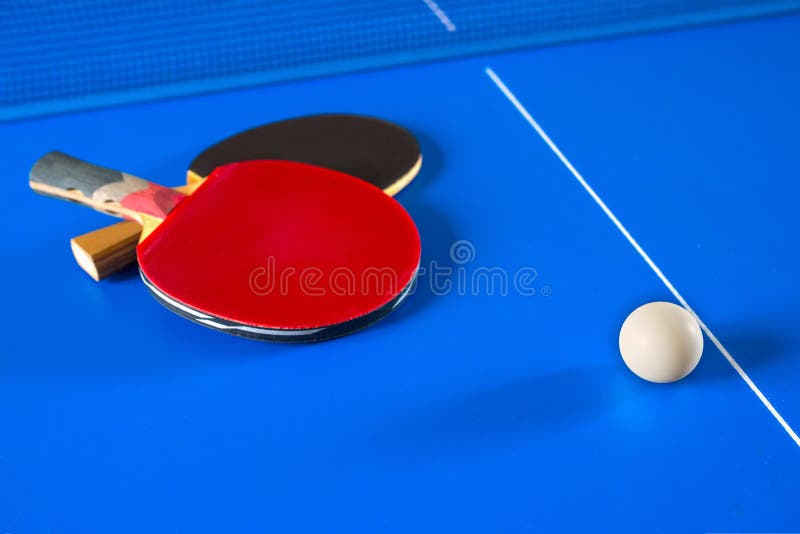 Sport games in Ping Pong. Rackets for table tennis and a ball on the blue table royalty free stock photography Sport games in Ping Pong. Rackets for table tennis and a ball on the blue table royalty free stock photography