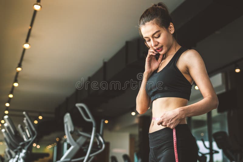 Sport gelukkige slanke vrouw die taillemeetlint op fitness de achtergrond van het de club opleidingscentrum van de gymnastiekspor royalty-vrije stock afbeeldingen Sport gelukkige slanke vrouw die taillemeetlint op fitness de achtergrond van het de club opleidingscentrum van de gymnastiekspor royalty-vrije stock afbeeldingen
