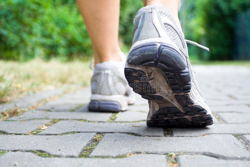 Donna che cammina sul marciapiede, scarpe sportive close-up.