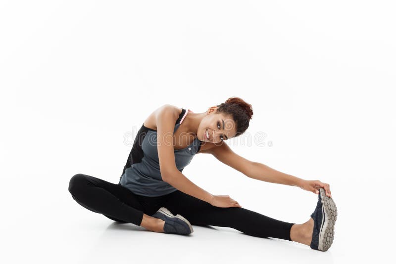 Sport, training, lifestyle and Fitness concept - portrait of beautiful happy African American woman stretching leg while stock photo Sport, training, lifestyle and Fitness concept - portrait of beautiful happy African American woman stretching leg while stock photo