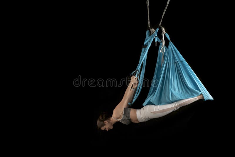 Sport woman practices aerofly yoga while hangs upside down. Inverted pose. Aero anti gravity yoga. Black background stock photo