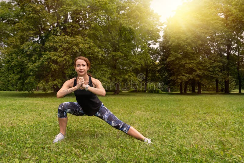 Sport woman wearing exercise suit doing stretching fitness exercise in city park at green grass stock photo Sport woman wearing exercise suit doing stretching fitness exercise in city park at green grass stock photo