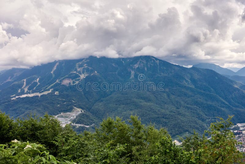 Sportanlagen und Wohngebäude auf die Steigung eines hohen Berges mit einer grünen Steigung und die Oberseite in den Wolken Sport stockbilder Sportanlagen und Wohngebäude auf die Steigung eines hohen Berges mit einer grünen Steigung und die Oberseite in den Wolken Sport stockbilder