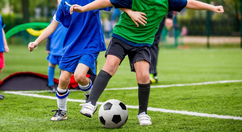 Sportar för barnlek Ungar som sparkar fotbollsmatchen Unga pojkar som spelar fotboll på graden för grönt gräs Ungdomsportcompetit arkivbilder