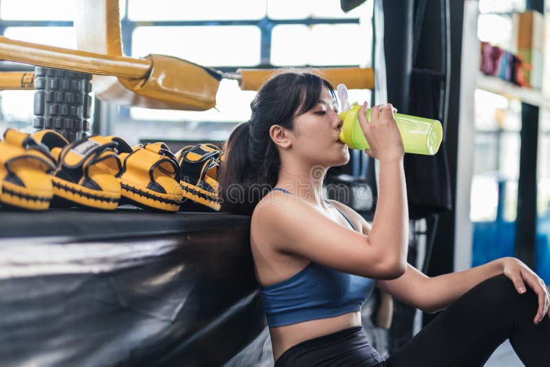 Sportief jonge aziatische vrouw na een geslaagde fitness gym holding fles met eiwit schudden