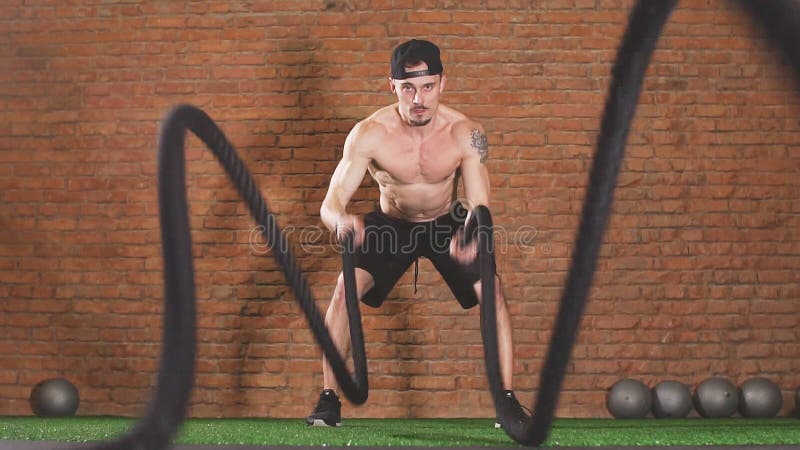 Sportif avec cordes de combat en corde de bataille exercice dans la salle de fitness, ralenti