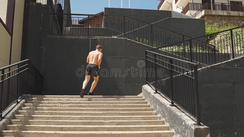 Sportif caucasien courant vers le haut avec de l'énergie sur l'escalier urbain