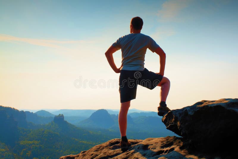Sportif dans la chemise et le pantalon L'homme se tient sur la crête de la falaise de grès dans des empires de roche se garent et photographie stock Sportif dans la chemise et le pantalon L'homme se tient sur la crête de la falaise de grès dans des empires de roche se garent et photographie stock