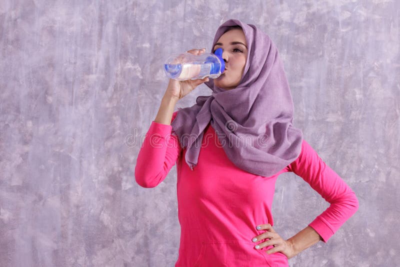 Sportig kvinna för härlig hijab som dricker mineralvatten efter workou fotografering för bildbyråer