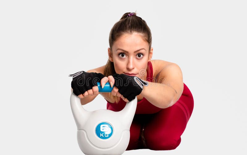 Sportiva muscolare che si scalda prima di un allenamento intenso con la campana del bollitore su fondo bianco sicuro - immagine fotografia stock libera da diritti Sportiva muscolare che si scalda prima di un allenamento intenso con la campana del bollitore su fondo bianco sicuro - immagine fotografia stock libera da diritti