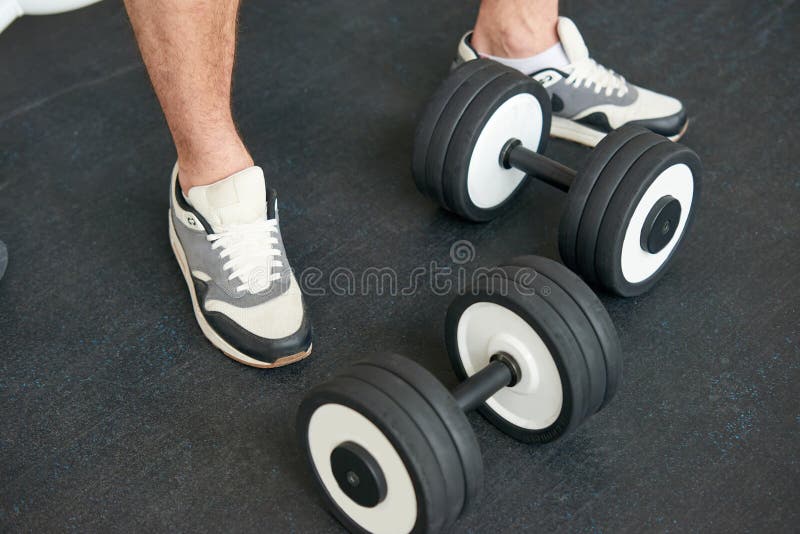 Sportivo in scarpe da tennis che stanno con le teste di legno sul pavimento fotografia stock libera da diritti Sportivo in scarpe da tennis che stanno con le teste di legno sul pavimento fotografia stock libera da diritti