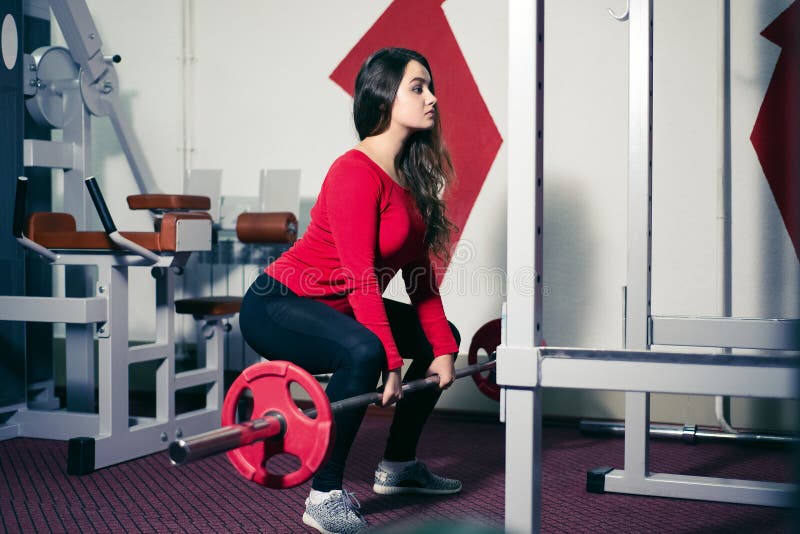 Sportowa dziewczyna trzyma barbell w jego ręki piękna kobieta robi fizycznym ćwiczeniom kuca z prostym plecy w gym sport zdjęcie royalty free Sportowa dziewczyna trzyma barbell w jego ręki piękna kobieta robi fizycznym ćwiczeniom kuca z prostym plecy w gym sport zdjęcie royalty free