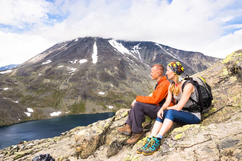 Sportpar som fotvandrar på Besseggen Fotvandrare tycker om den härliga sjön och bra väder i Norge arkivbilder Sportpar som fotvandrar på Besseggen Fotvandrare tycker om den härliga sjön och bra väder i Norge arkivbilder