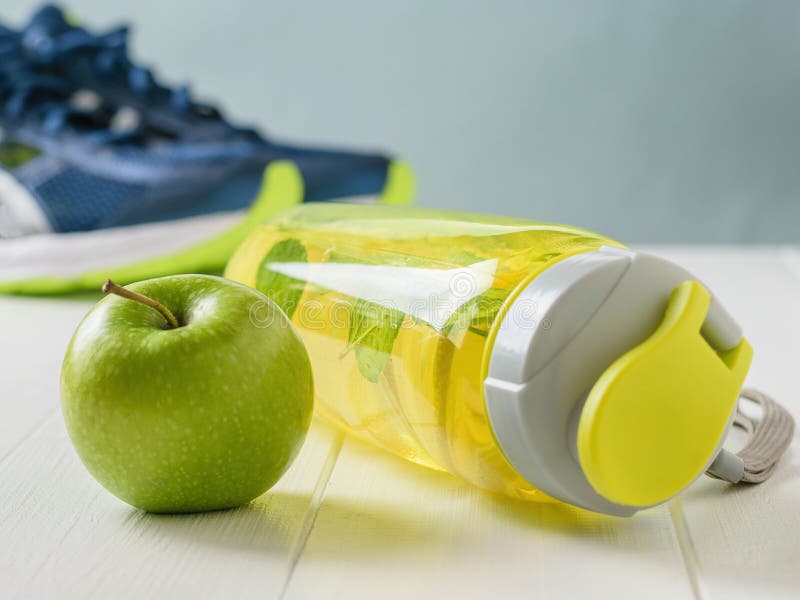 Sports bottle with a refreshing drink and a green Apple on the background of running shoes. stock photography Sports bottle with a refreshing drink and a green Apple on the background of running shoes. stock photography
