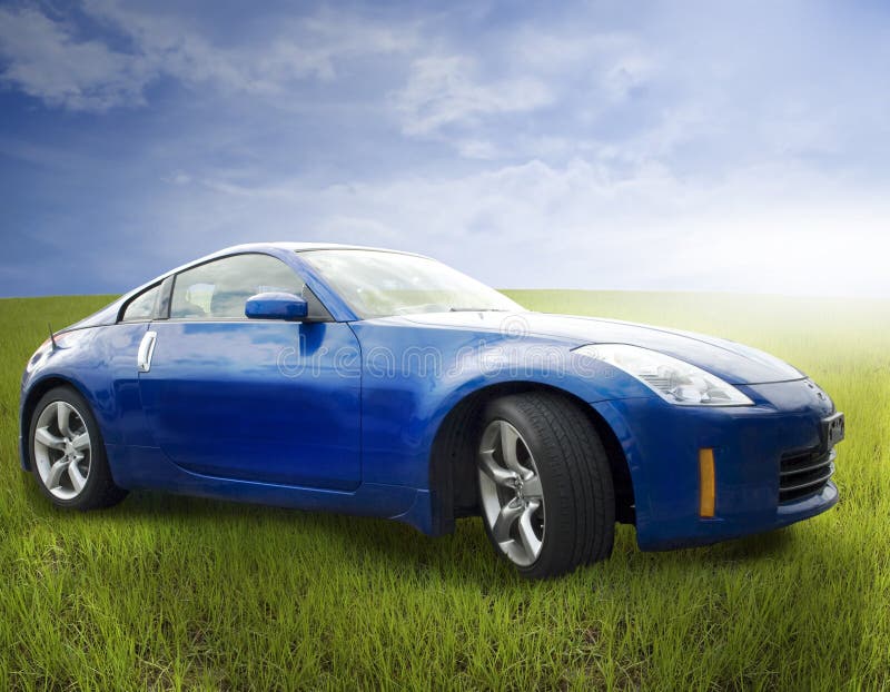 A bright blue sports car sitting in a field of grass under a cloudy sky.