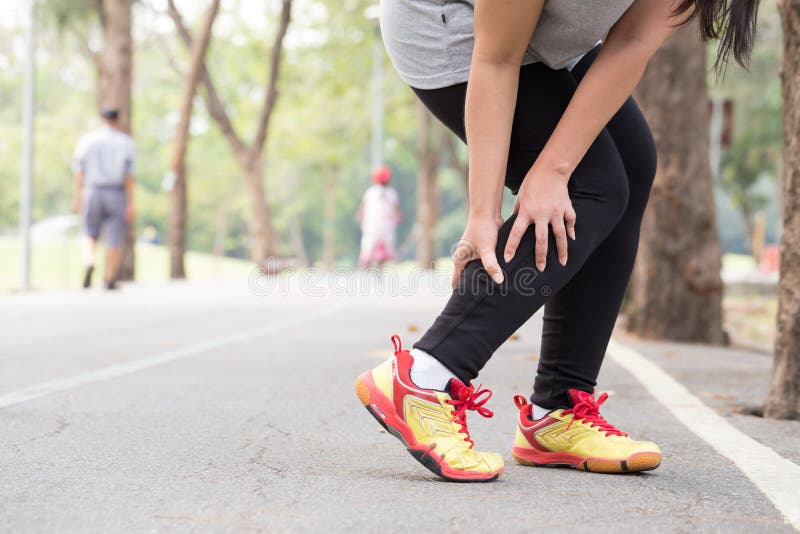 Sports injury. Cramp. Woman holding sore leg muscle while jogging in the park