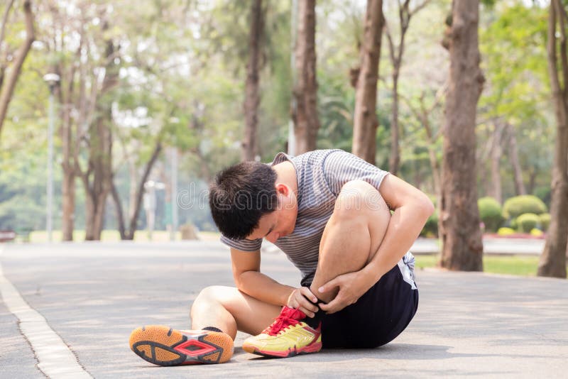 Sports injury. Man with pain in ankle while jogging in park