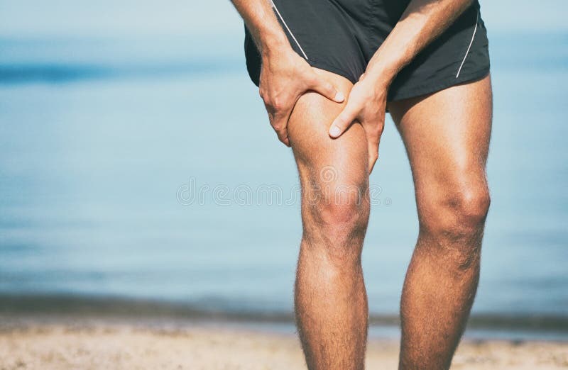 Sports injury muscle cramp pain fit runner man athlete holding painful thigh leg on outdoor summer jogging exercise