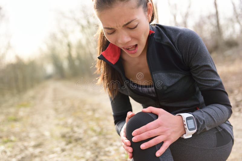 Sport and fitness injury - Female runner with hurting knee. Running woman screaming in pain during run wearing a smartwatch. Painful joint during workout. Sport and fitness injury - Female runner with hurting knee. Running woman screaming in pain during run wearing a smartwatch. Painful joint during workout.