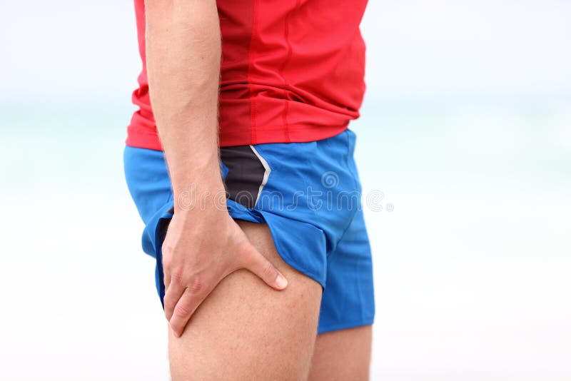 Sports injury. Running muscle stain injury in thigh. Closeup of runner touching leg in muscle pain. Sports injury. Running muscle stain injury in thigh. Closeup of runner touching leg in muscle pain.