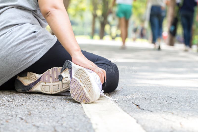 Sports injury. Woman with pain in ankle while jogging in the park