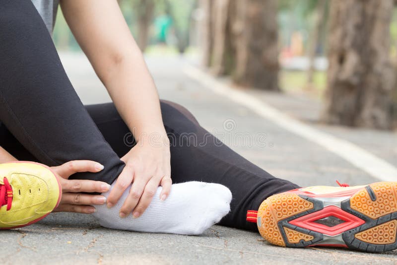 Sports injury. Woman with pain in ankle while jogging in park