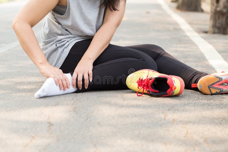 Sports injury. Woman with pain in ankle while jogging in park