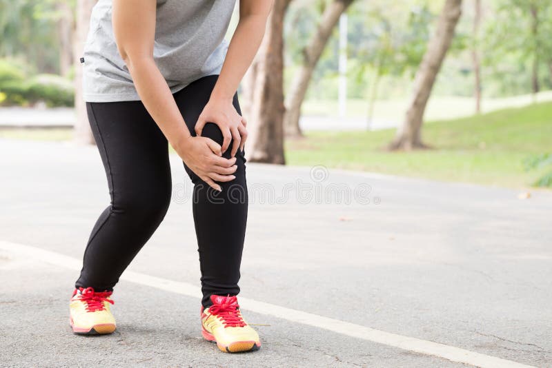 Sports injury. Woman with pain in knee while jogging in park