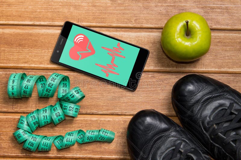 Sportskor, Apple och att mäta bandet och en telefon med det vård- kortet på en träbakgrund Mobil vård- avkännare för app för att royaltyfri fotografi Sportskor, Apple och att mäta bandet och en telefon med det vård- kortet på en träbakgrund Mobil vård- avkännare för app för att royaltyfri fotografi