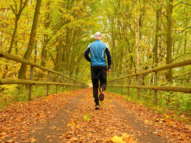 Sportsman in blue t-shirt and black trousers run on road. The man is slowly running stock photos Sportsman in blue t-shirt and black trousers run on road. The man is slowly running stock photos
