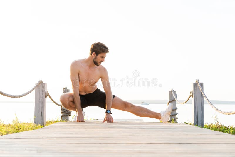 Portrait of handsome young man stretching legs before exercise run outdoors.